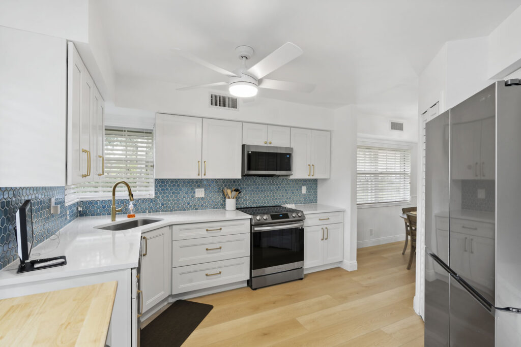 Kitchen remodel with white shelves,, wooden floor and blue tile backsplash