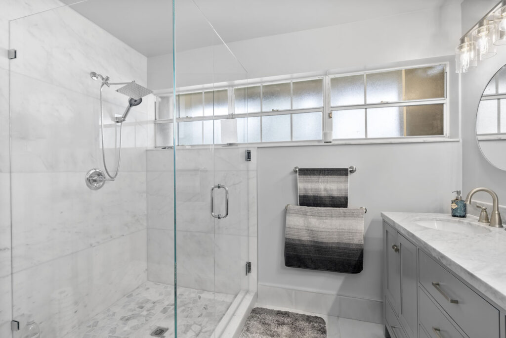 Bathroom remodel with clear glass shower and rainforest showerhead.