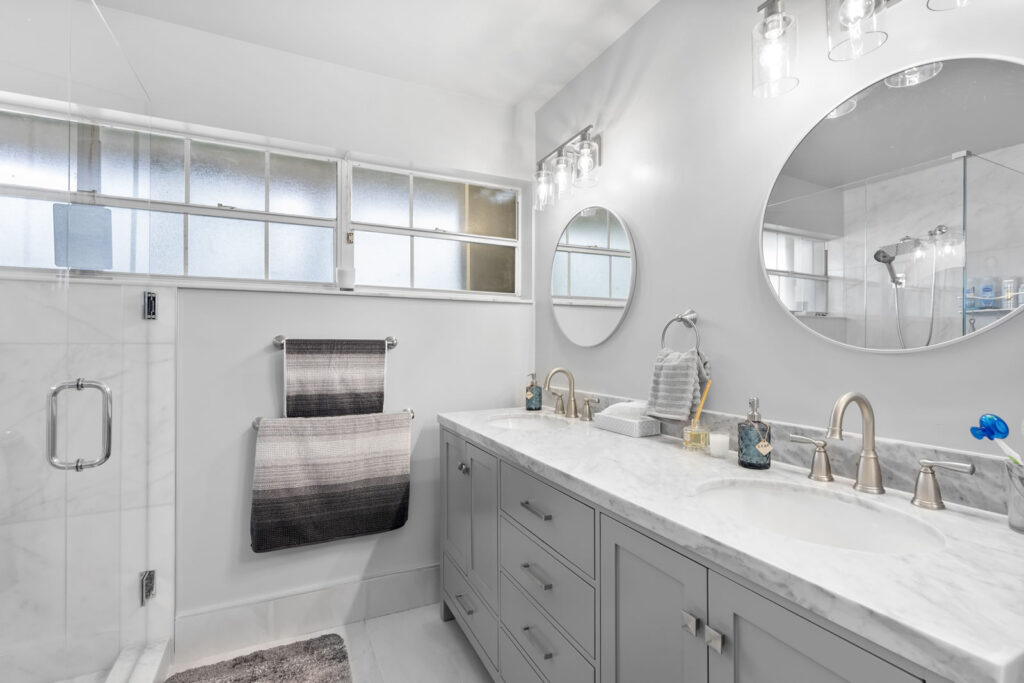 Beautiful bathroom remodel with twin faucets and twin round mirrors.